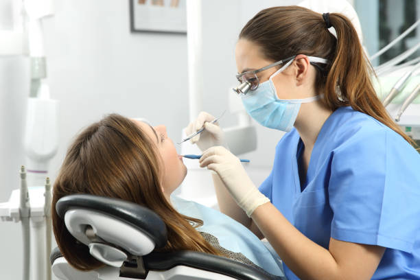 Dentist examining a patient teeth Dentist wearing eyeglasses gloves and mask examining a patient teeth with a dental probe and a mirror in a clinic box with equipment in the background human teeth photos stock pictures, royalty-free photos & images