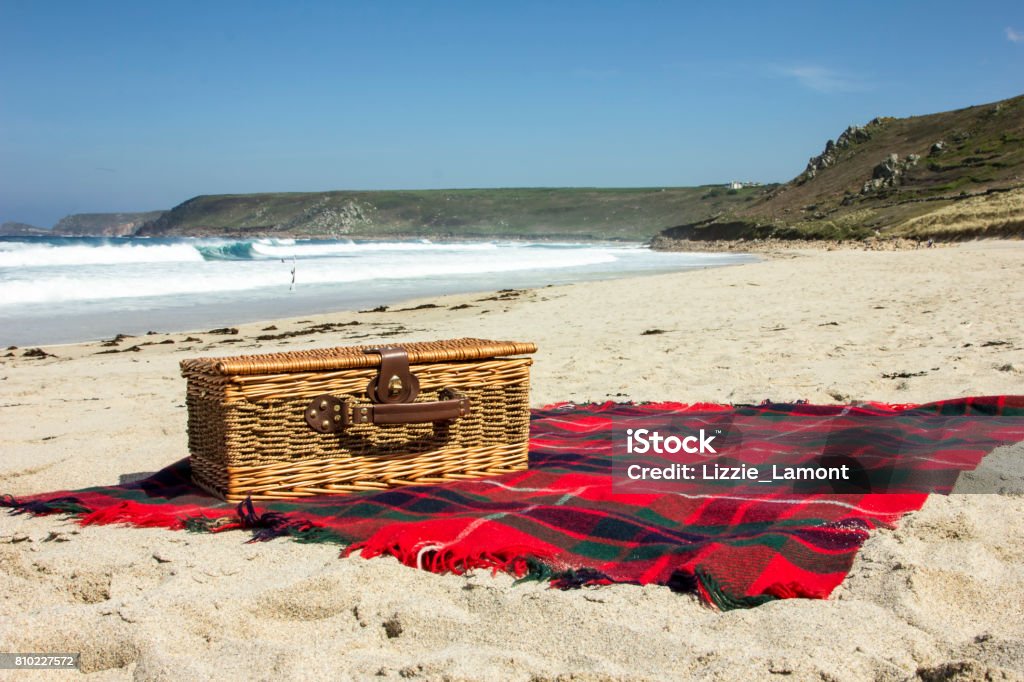 Picnic on the beach Landscape colour photo of a traditional wicker picnic basket on a tartan rug laid out on a sandy beach Picnic Stock Photo