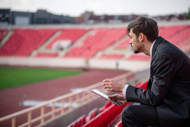 giovane seduto sulla tribuna dello stadio - strategy coach soccer digital tablet foto e immagini stock