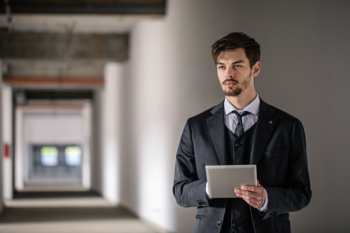 Manager man standing in stadium hallway and holding digital tablet