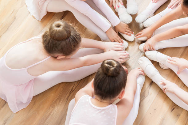 bailarinas irreconhecíveis sentar-se com os pés juntos ao tocar os dedos dos pés - round bale - fotografias e filmes do acervo