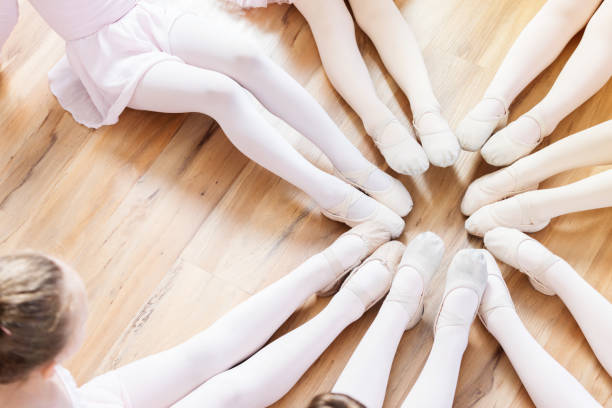 Unrecognizable ballerinas sit in a circle with their feet together A group of ballerinas, with only legs and one head showing, sit on the floor in a circle with their legs extended and their pointed toes together. ballet dancer feet stock pictures, royalty-free photos & images