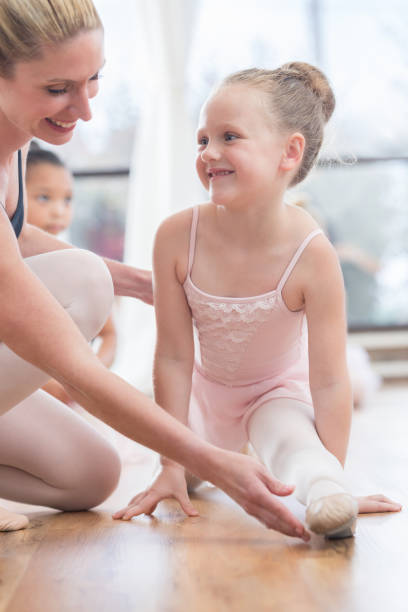 istock Young ballerina receives guidance from instructor on toe pointing 810242842