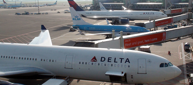 View Parked Delta Airlines Airplane,KLM Royal Dutch Airlines Airplane,Hop Airline Airplane,Ground Staff Equipment On The Ground,Advertising Sign At Loading,Unloading Gate Of Amsterdam Schiphol International Airport In The Netherlands Western Europe