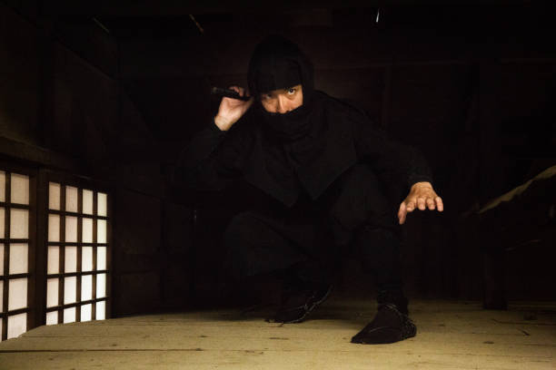 istock Japanese ninja in black costume hiding a dark attic 810275888