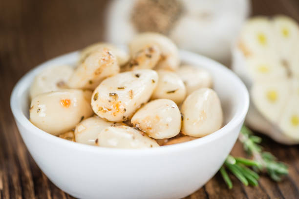 Roasted garlic on cheese and crackers.  Focus on whole garlic head.