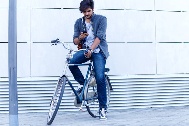 istock Young handsome guy on a bicycle looking at mobile phone. 810296580