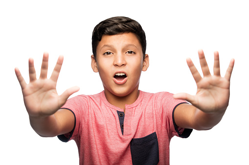 Latin teenage boy raising both hands in front of him, looking at the camera and opening his mouth.