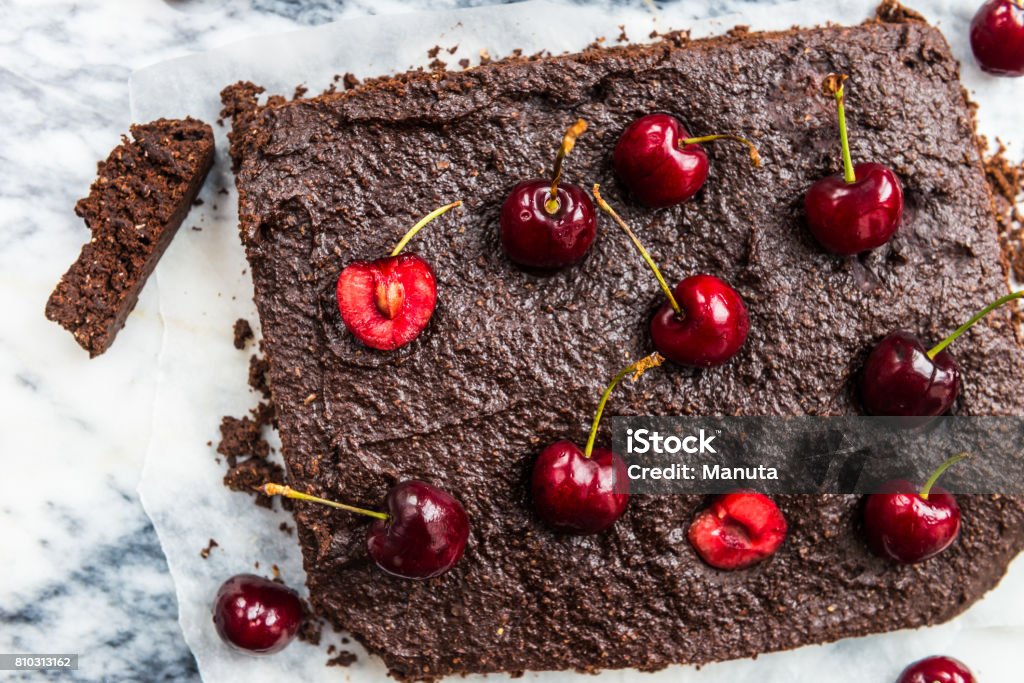 Double Chocolate Brownies with Cherries Healthy Double Chocolate Brownies with Cherries. Made from Banana, Wholewheat and Coconut Flour and Maple Syrup. Vegan concept. Top View, marble background Backgrounds Stock Photo