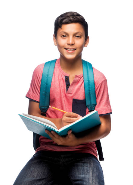 Happy teenage schoolboy sitting with notebook and smiling stock photo