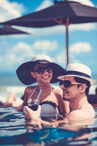 istock Couple Drinking Cocktail and Enjoying Sunset in Infinity Swimming Pool 810313250