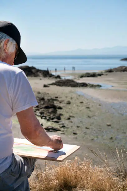 Man drawing with oil pastels, at the beach