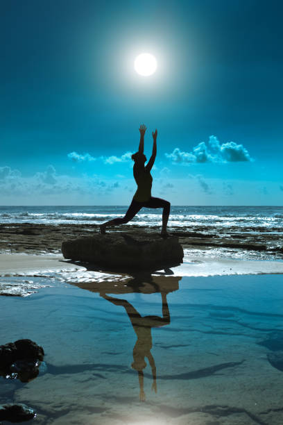 Woman Practicing Yoga Pose On The Beach At Sunrise In Kauai