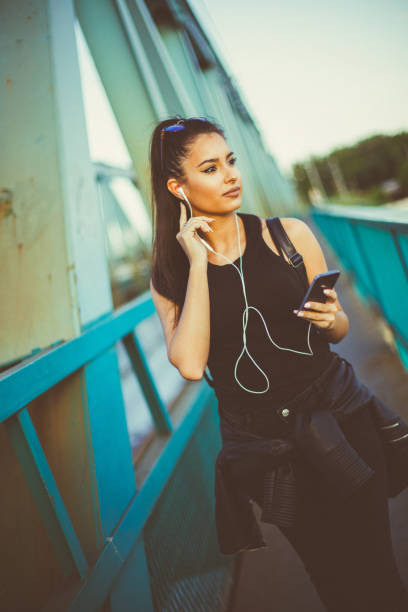 hermosa chica caminando y escuchando música en el puente - grand river audio fotografías e imágenes de stock