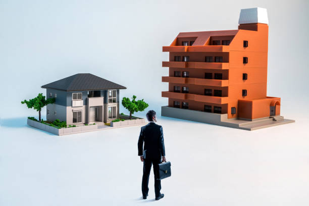 businessman looking at a house and a apartment building. businessman looking at a house and a apartment building. diorama photos stock pictures, royalty-free photos & images