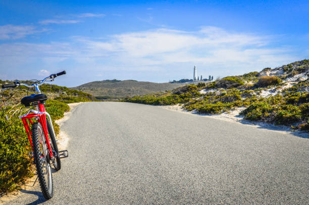 The Road to Lighthouse Parker's Point Road leading to Wadjemup Lighthouse in Rottnest Island, Western Australia with a bike parked on the roadside rottnest island photos stock pictures, royalty-free photos & images