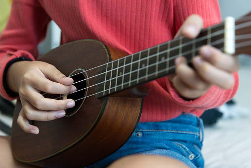 Close up of view of little girl's hand playing ukulele