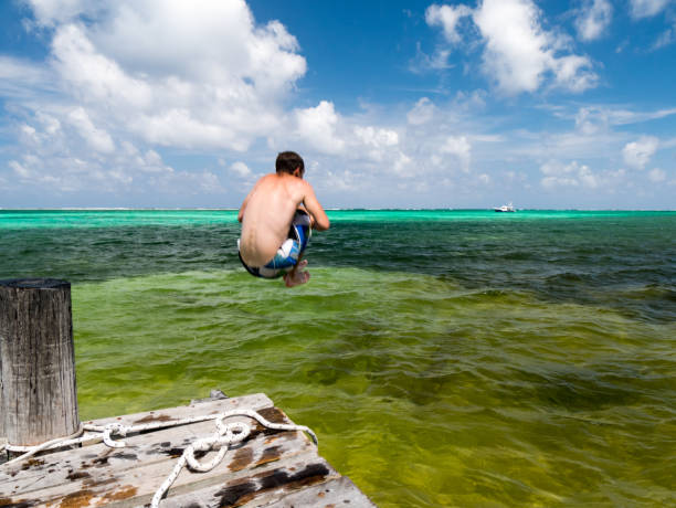 istock Young man jumps in carribean paradise ocean 810464296