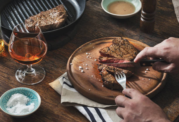 człowiek zjada grillowany stek przy drewnianym stole - steak sirloin steak dinner healthy eating zdjęcia i obrazy z banku zdjęć