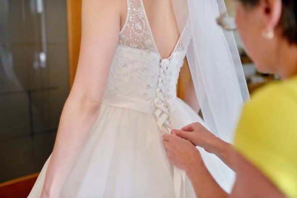 istock Bridesmaid is lacing white wedding dress for beautiful bride 810469086