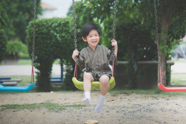 istock Asian child in kimono playing on swing i 810469276