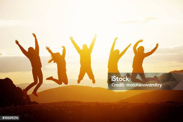 Happy Friends Jumping Sunset Mountains Stock Photo - Download Image Now - Jumping, Joy, People