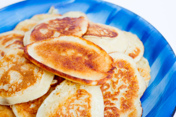 istock Ruddy freshly cooked pancakes lie on a blue plate on a white background. 810512076