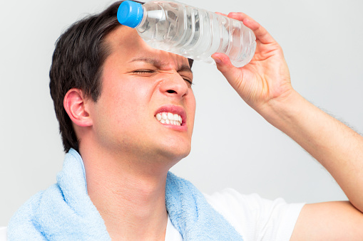 heatstroke concept. a young man cooling his head with a bottle of water.