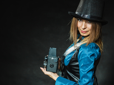 Photography and retro style. Young vintage attractive girl holds old aged camera. Steampunk photographer taking photo.