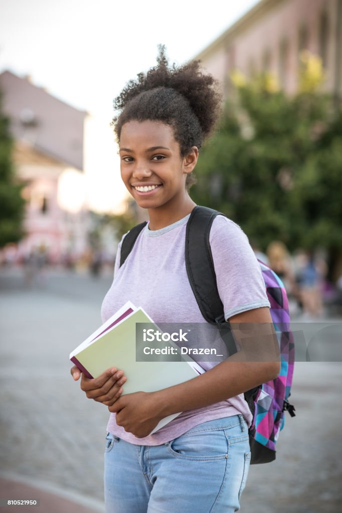 Teenage African girl with books going to school. September is getting closer and school children and high school students are getting ready for the responsibilities and tasks. Beautiful black girl with books and backpack going to school. African-American Ethnicity Stock Photo
