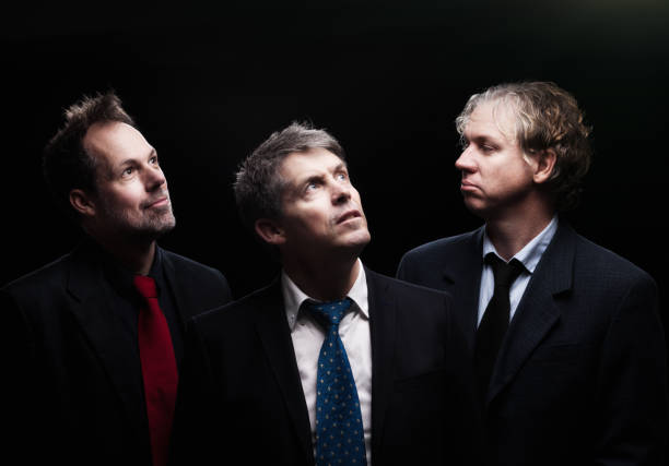 istock Three businessmen pose for portrait against black 810524382