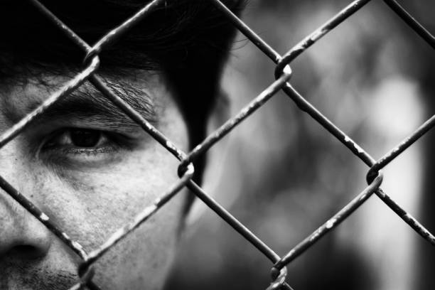 istock Depressed man standing behind a fence ,close up on face 810524712