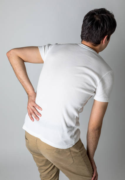 若い男の背中の下部に痛みがあります。 - lower back pain ストックフォトと画像