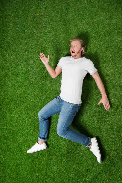istock young casual man lying in funny position on the grass 810533042