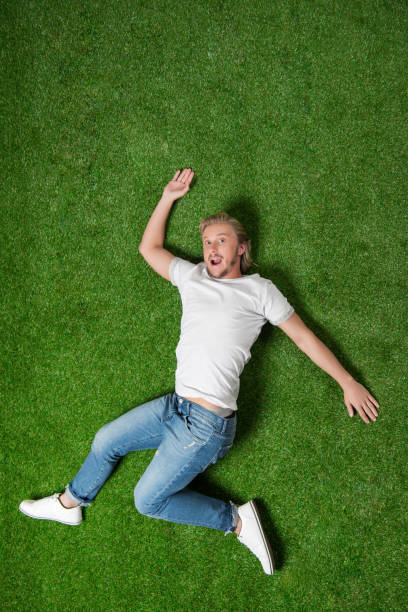 istock casual man with facial expression lying in funny position on meadow 810539296