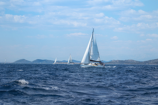 Many small sailboats sail on Lake Lago di Garda in Italy