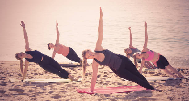istock Positive girls practicing yoga asana on sandy beach 810543088