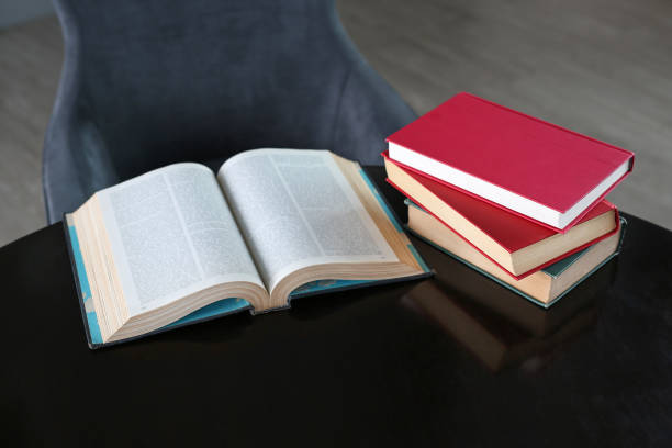 istock Open book and stack of hardcover books on wooden table. 810557196