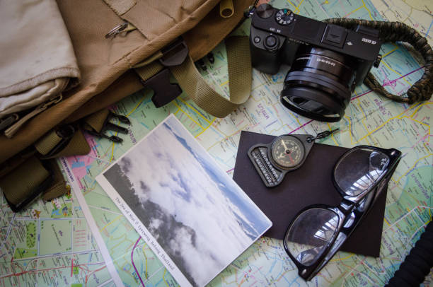 Hiking accessories set on wooden background with bag camera postcard glasses compass
