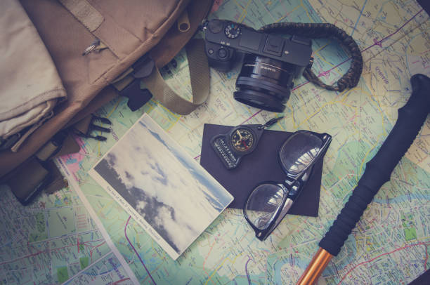 istock Hiking accessories set on wooden background with bag camera postcard glasses compass 810559482