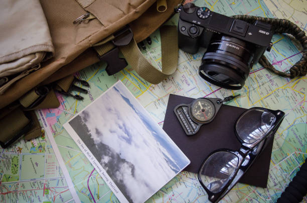 istock Hiking accessories set on wooden background with bag camera postcard glasses compass 810559528