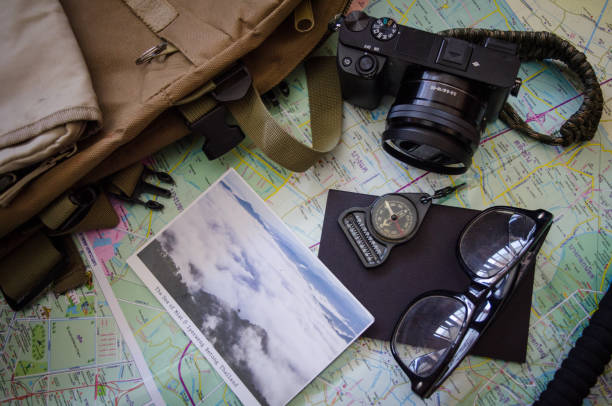 istock Hiking accessories set on wooden background with bag camera postcard glasses compass 810559572
