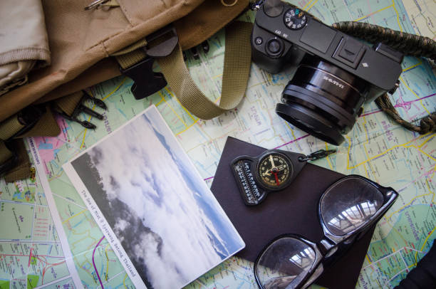 istock Hiking accessories set on wooden background with bag camera postcard glasses compass 810559628