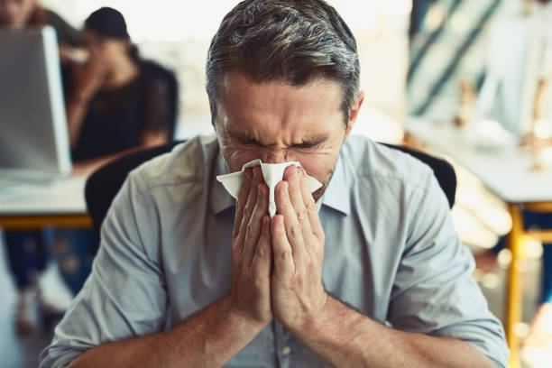 Allergies are just the worst Shot of a businessman blowing his nose in an office cold and flu man stock pictures, royalty-free photos & images