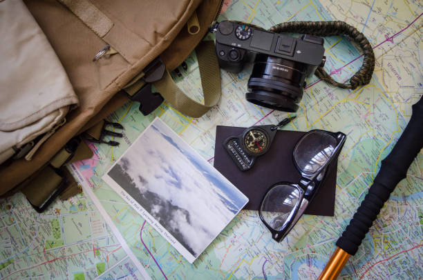 istock Hiking accessories set on wooden background with bag camera postcard glasses compass 810559818