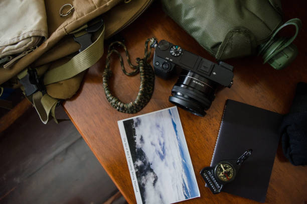 istock Hiking accessories set on wooden background with bag camera postcard glasses compass 810559882
