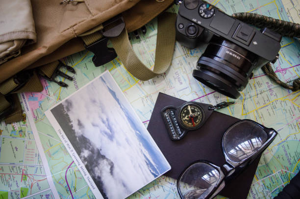 istock Hiking accessories set on wooden background with bag camera postcard glasses compass 810560552