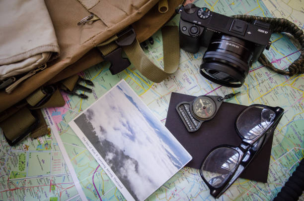 istock Hiking accessories set on wooden background with bag camera postcard glasses compass 810560996