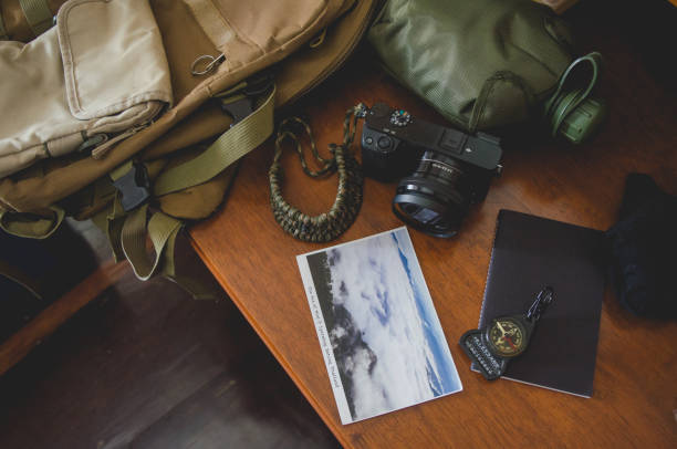 istock Hiking accessories set on wooden background with bag camera postcard glasses compass 810561208