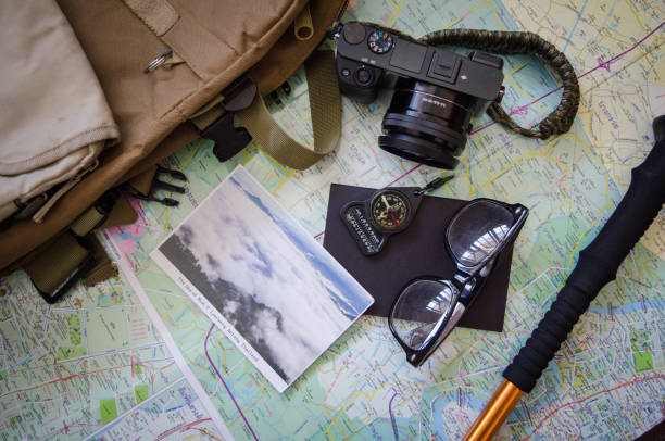 istock Hiking accessories set on wooden background with bag camera postcard glasses compass 810561284